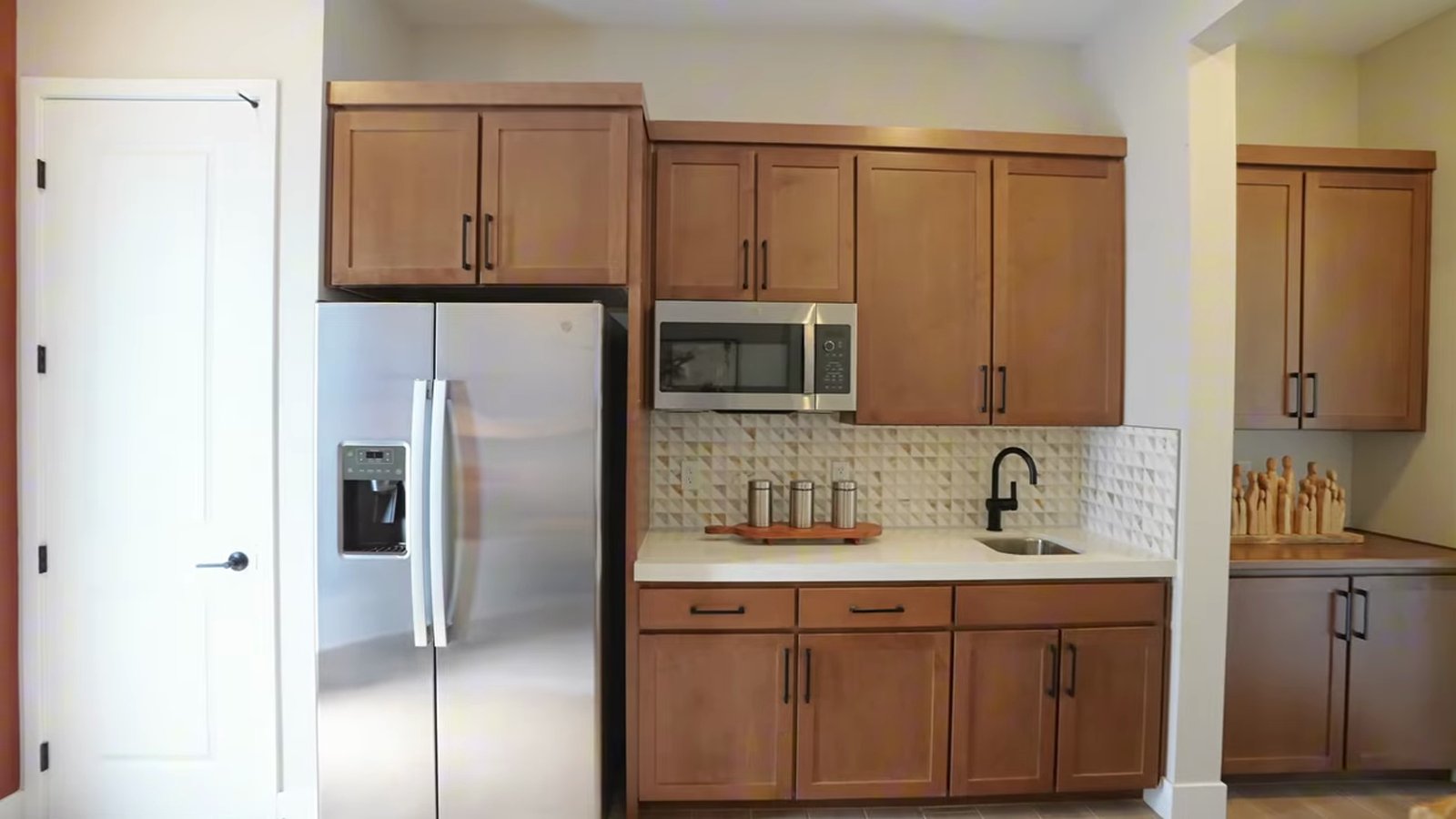 Kitchenette in the optional multi-gen suite of the Taylor Morrison Summit model with wood cabinets, a stainless refrigerator, microwave and sink