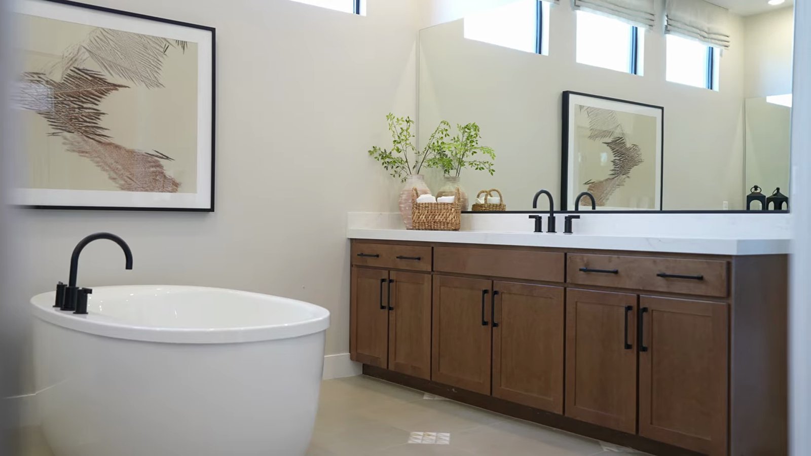 Primary bathroom in the Taylor Morrison Summit model at Ashland with a freestanding soaking tub, double vanity with dark cabinets and clerestory windows