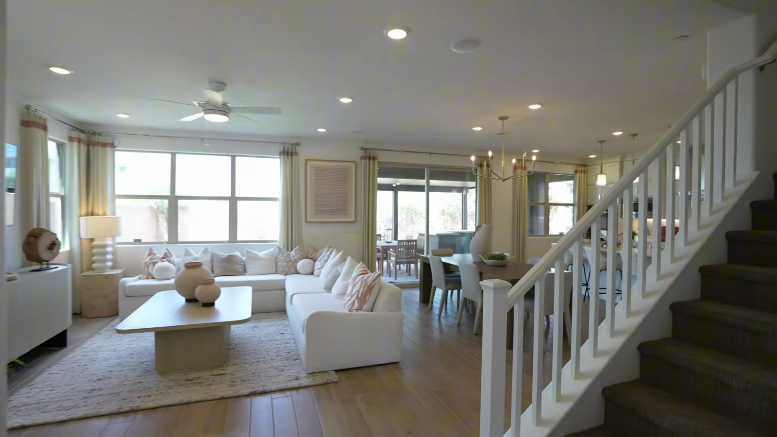 Woodside Aster great room at Ashwood with a white sectional, carpeted staircase and sliding doors to the covered patio