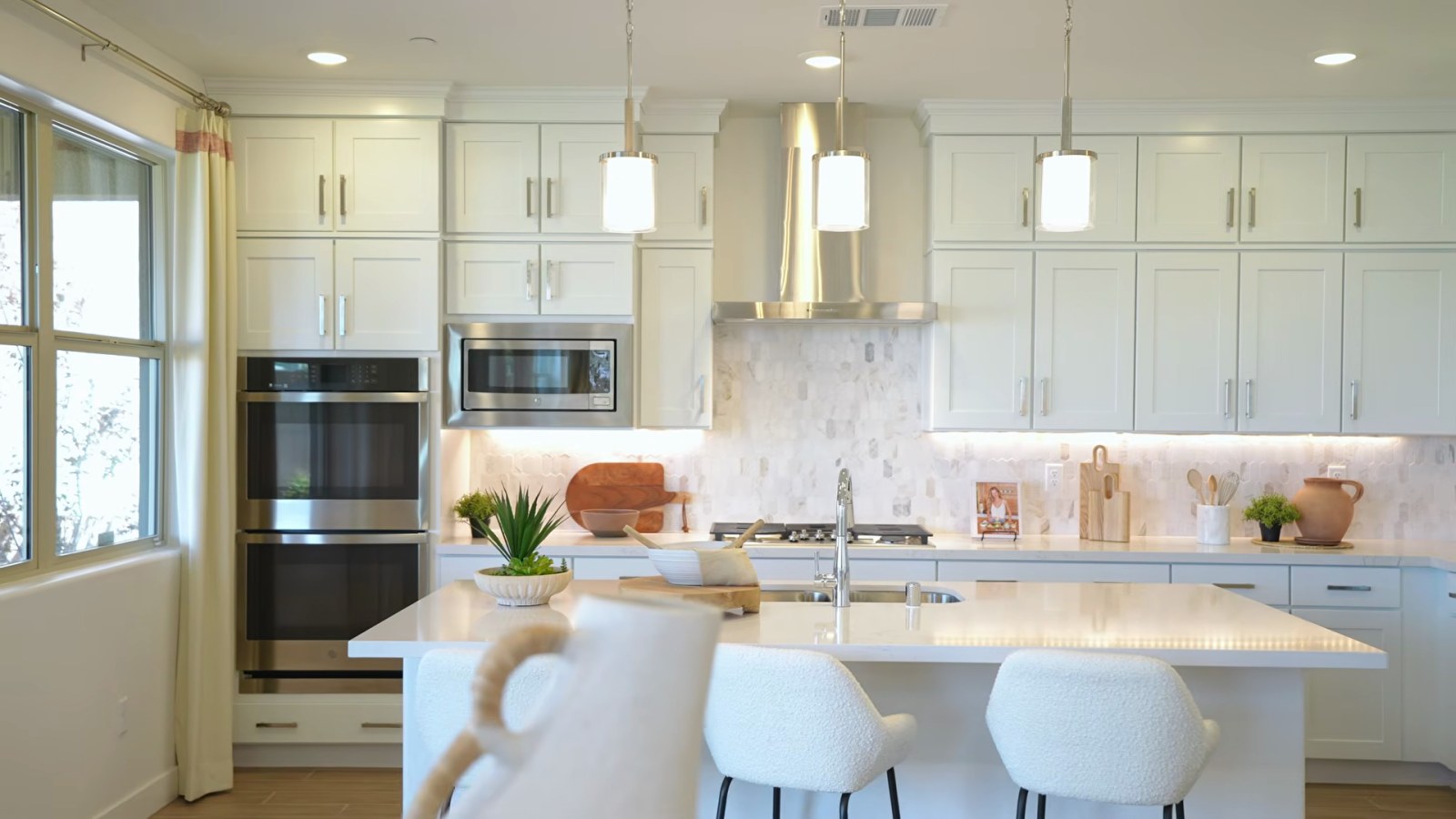 Woodside Aster model kitchen at Ashwood with white cabinets stacked to the ceiling, a double wall oven, a gas cooktop and a quartz island