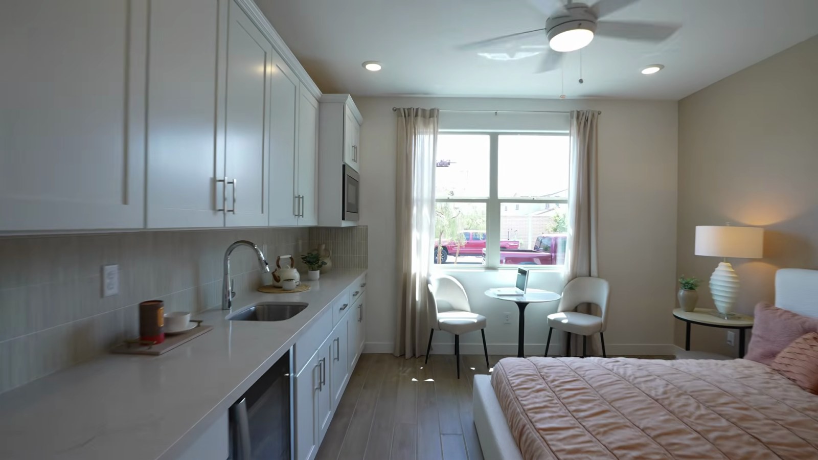 First-floor casita bedroom in the Woodside Aster model at Ashwood with a kitchenette counter, white cabinets and a queen bed