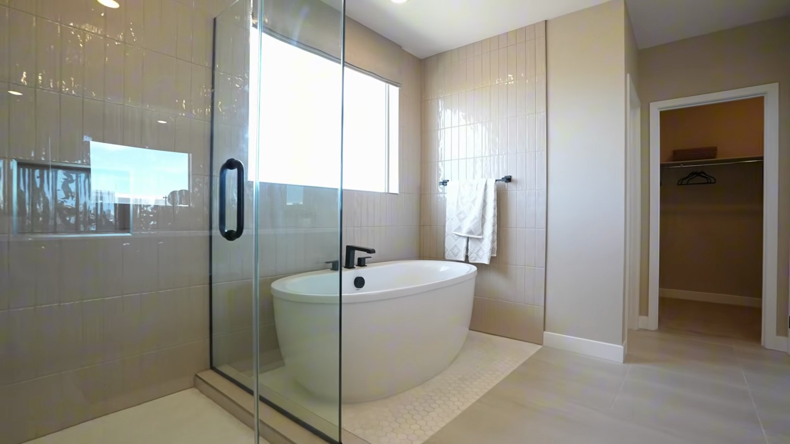Oakley primary bathroom at Ashwood with a freestanding soaking tub, a glass walk-in shower and wall tile to the ceiling