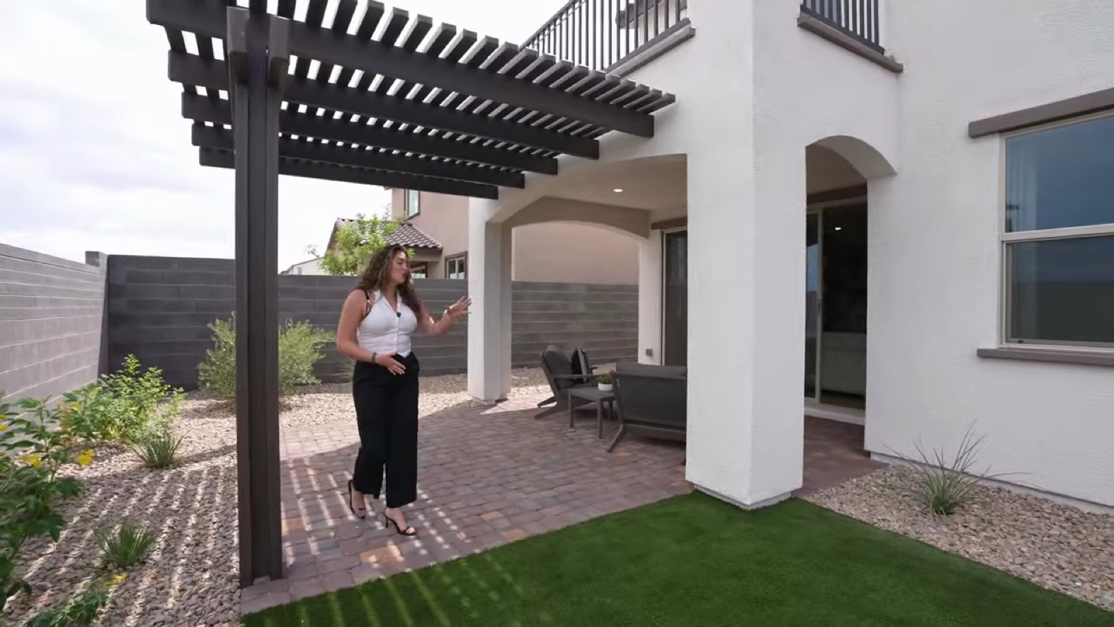 Oakley model backyard at Lyra at Sunstone with a pergola over pavers, artificial turf and desert landscaping inside block walls